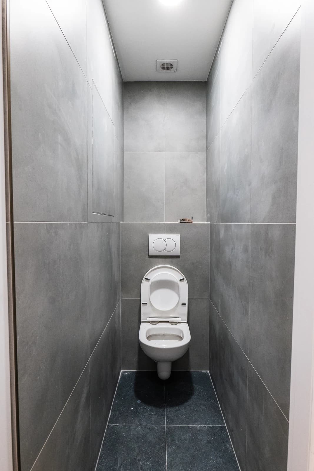 Štýlová tmavá kuchyňa s moderným osvetlením, zlatými akcentmi a elegantným jedálenským stolom.