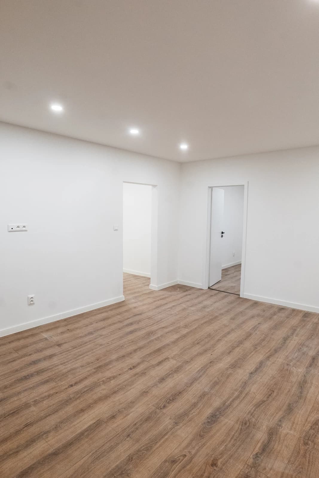 Štýlová tmavá kuchyňa s moderným osvetlením, zlatými akcentmi a elegantným jedálenským stolom.