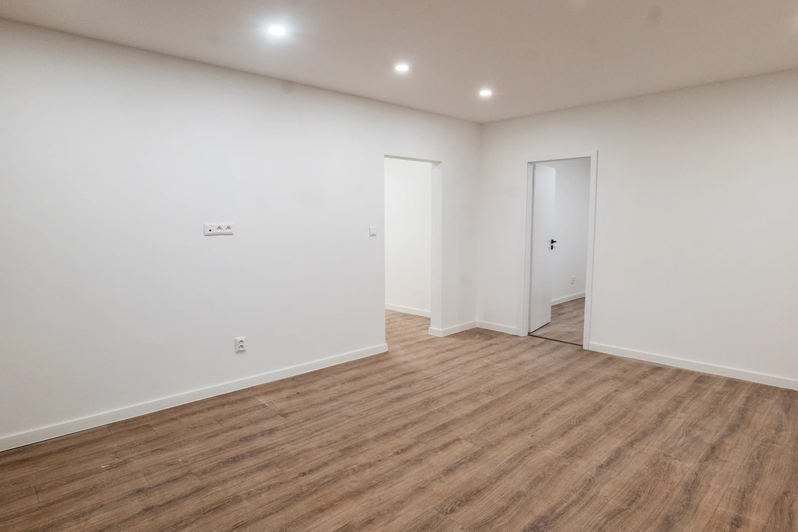 Štýlová tmavá kuchyňa s moderným osvetlením, zlatými akcentmi a elegantným jedálenským stolom.