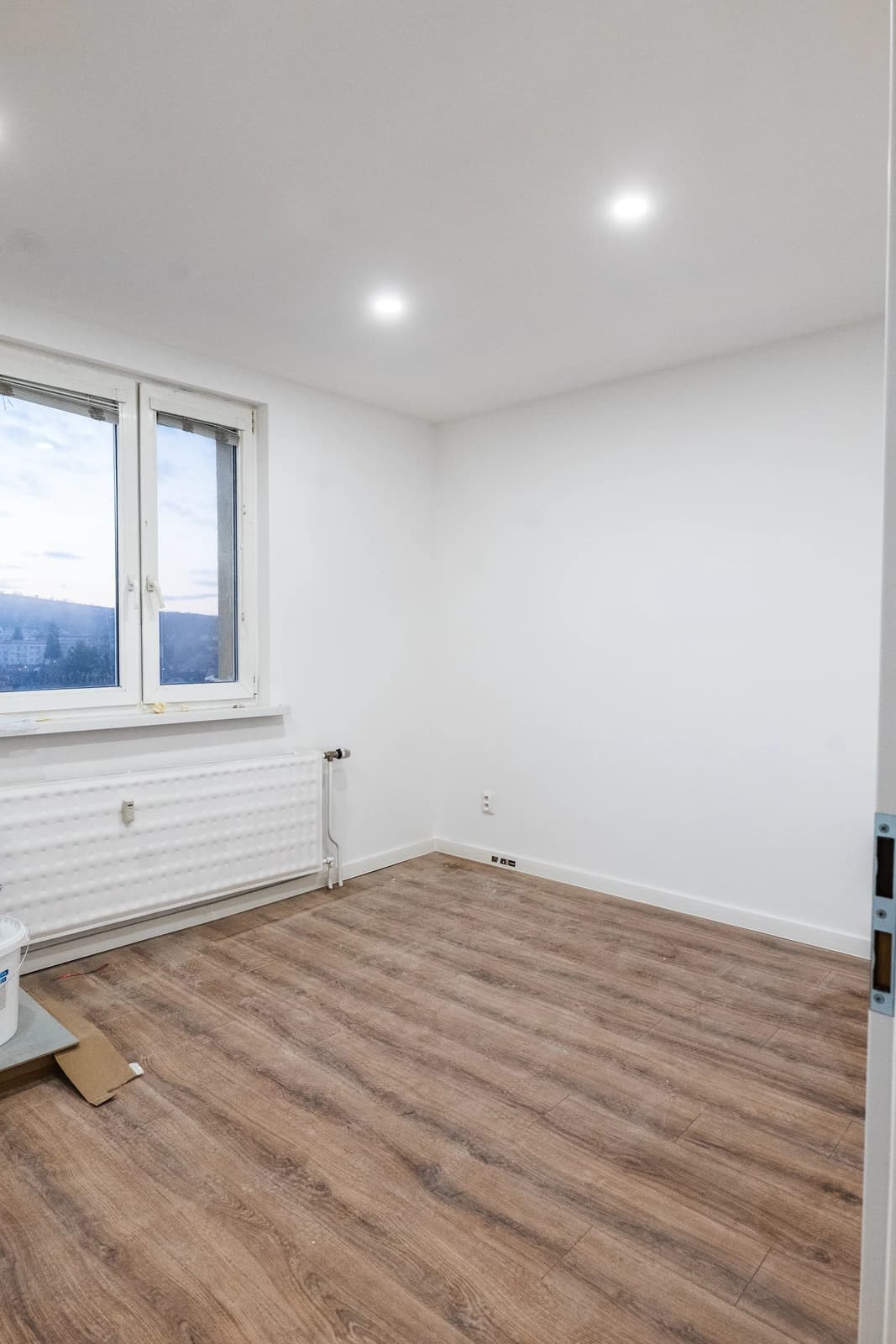 Štýlová tmavá kuchyňa s moderným osvetlením, zlatými akcentmi a elegantným jedálenským stolom.