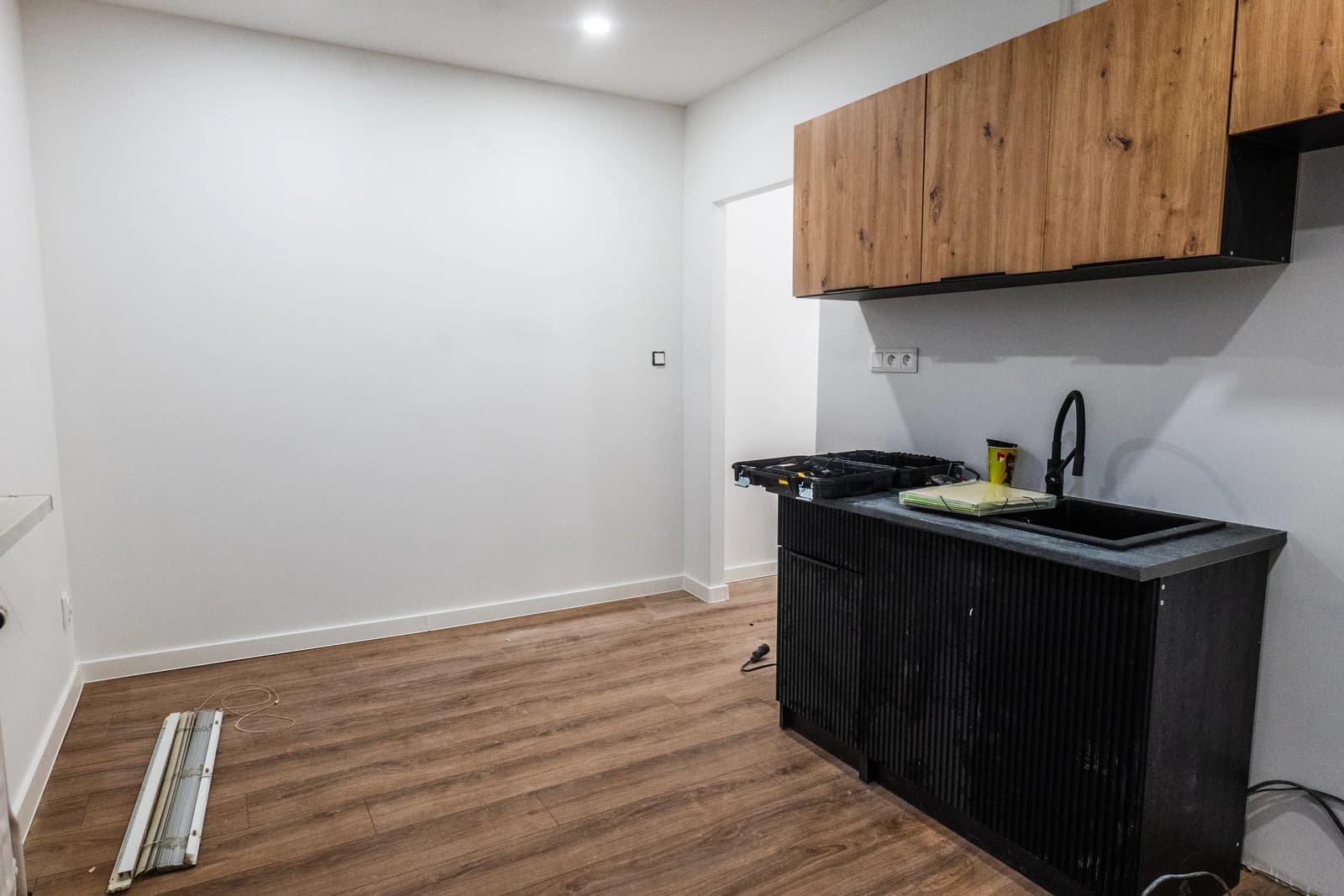 Štýlová tmavá kuchyňa s moderným osvetlením, zlatými akcentmi a elegantným jedálenským stolom.