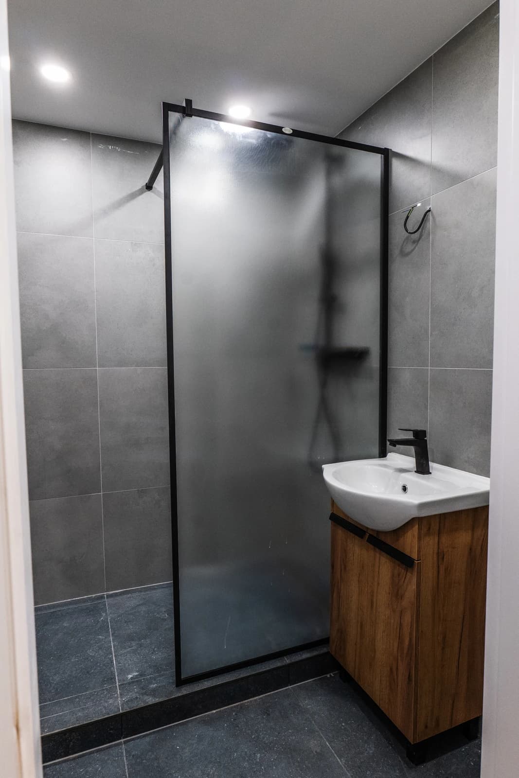 Štýlová tmavá kuchyňa s moderným osvetlením, zlatými akcentmi a elegantným jedálenským stolom.