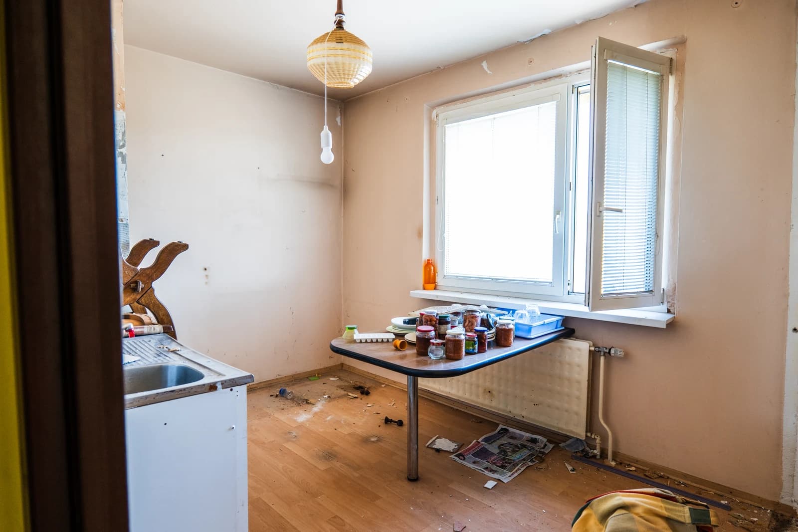 Štýlová tmavá kuchyňa s moderným osvetlením, zlatými akcentmi a elegantným jedálenským stolom.