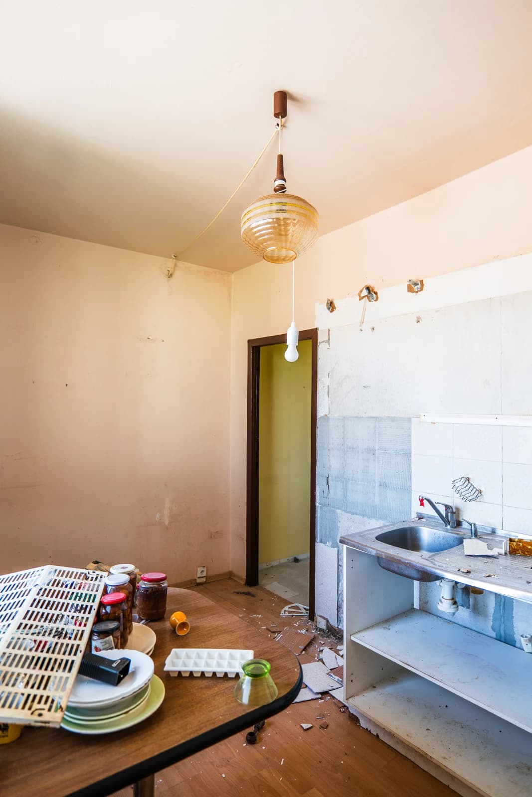 Štýlová tmavá kuchyňa s moderným osvetlením, zlatými akcentmi a elegantným jedálenským stolom.