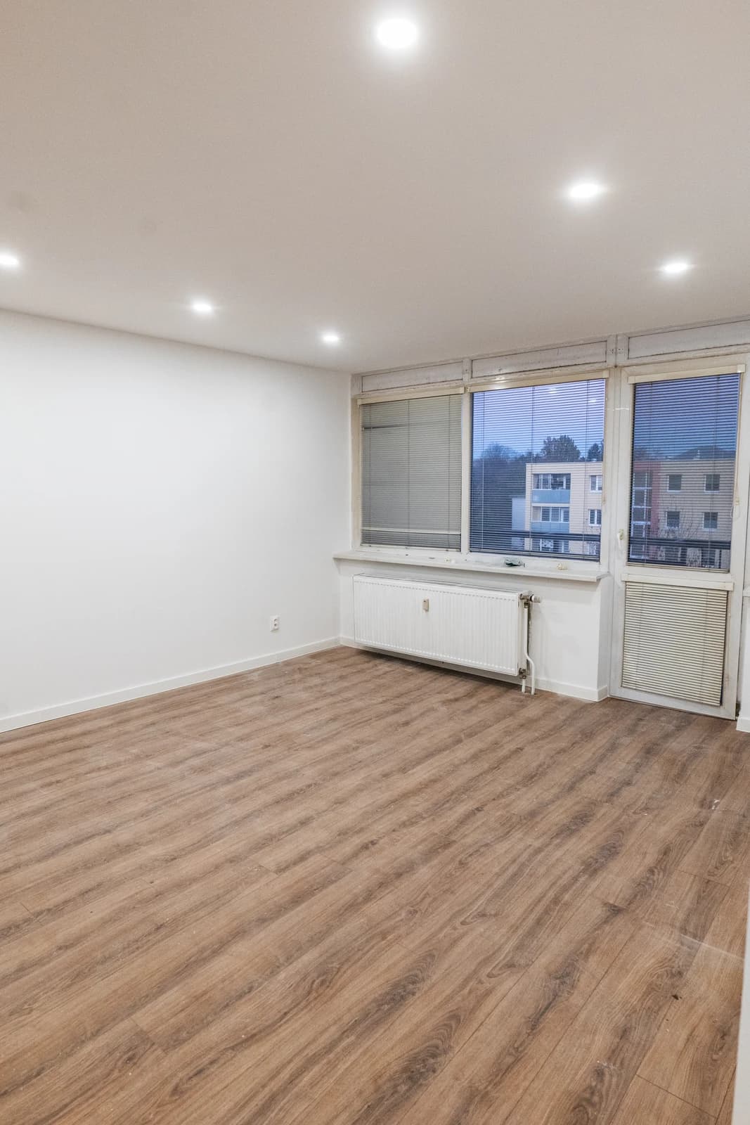 Štýlová tmavá kuchyňa s moderným osvetlením, zlatými akcentmi a elegantným jedálenským stolom.