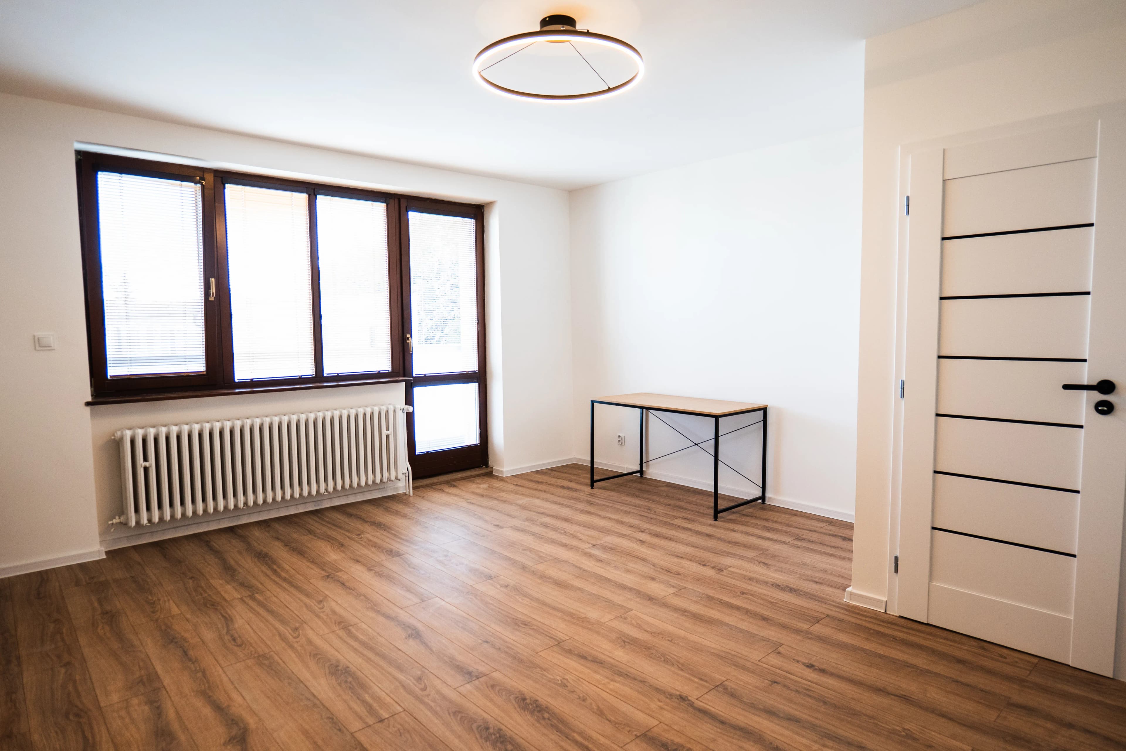 Moderná kancelária v minimalistickom štýle s elegantnými pracovnými stolmi a prírodnými materiálmi.