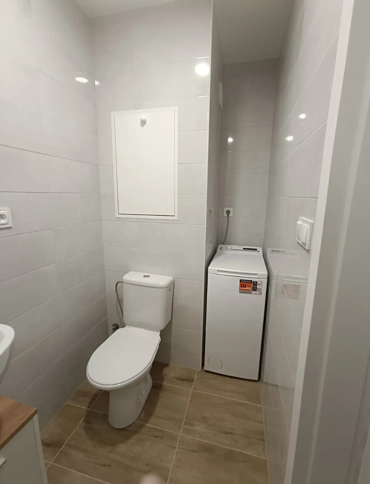 Štýlová tmavá kuchyňa s moderným osvetlením, zlatými akcentmi a elegantným jedálenským stolom.