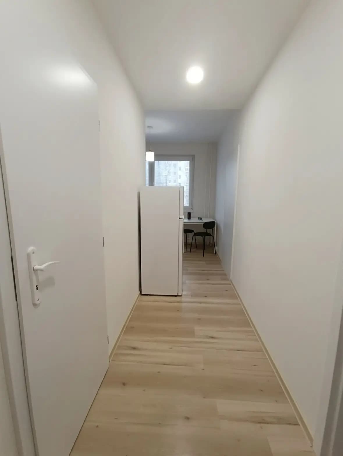 Štýlová tmavá kuchyňa s moderným osvetlením, zlatými akcentmi a elegantným jedálenským stolom.