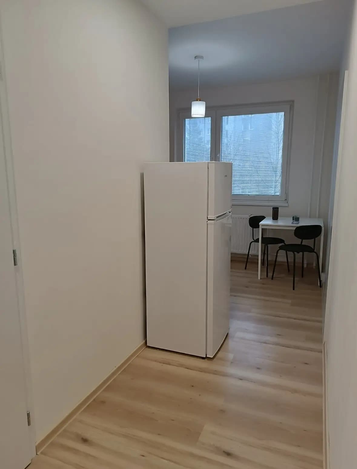 Štýlová tmavá kuchyňa s moderným osvetlením, zlatými akcentmi a elegantným jedálenským stolom.