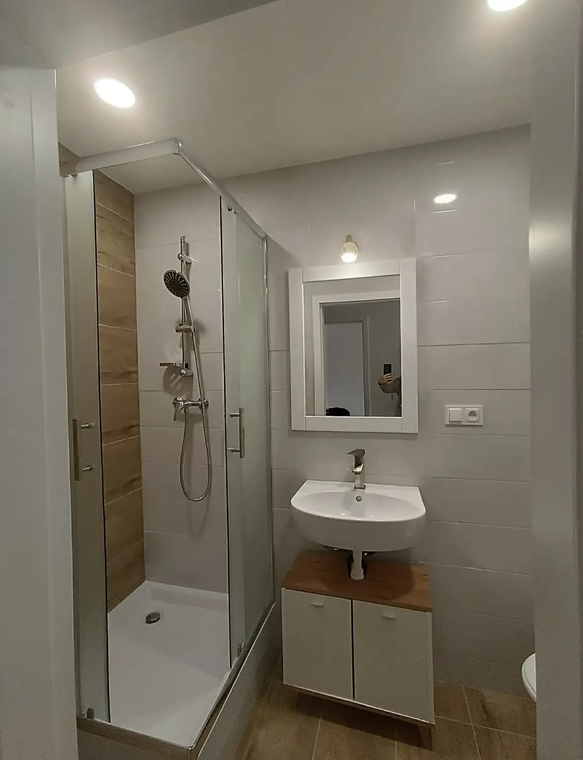 Štýlová tmavá kuchyňa s moderným osvetlením, zlatými akcentmi a elegantným jedálenským stolom.