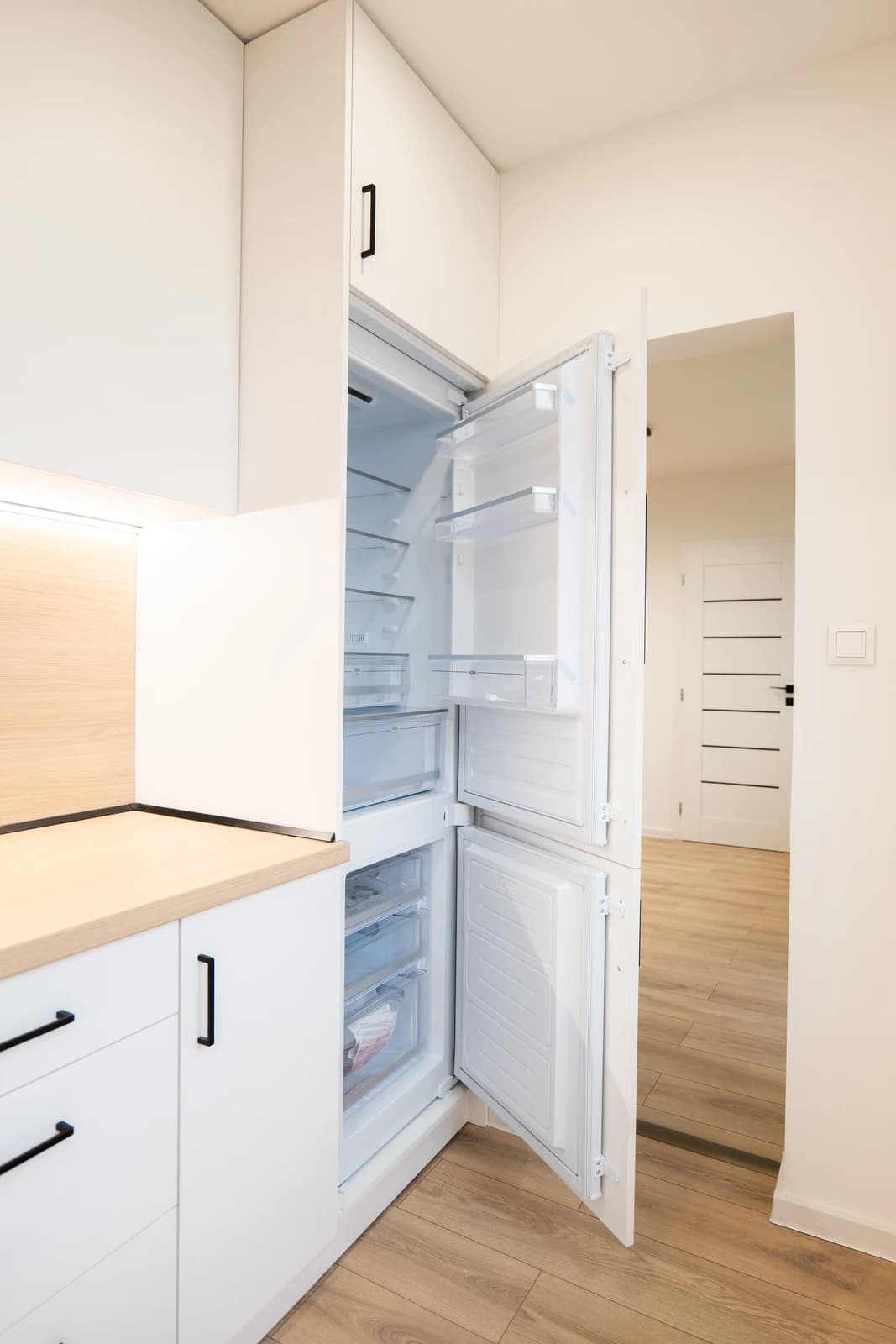 Štýlová tmavá kuchyňa s moderným osvetlením, zlatými akcentmi a elegantným jedálenským stolom.