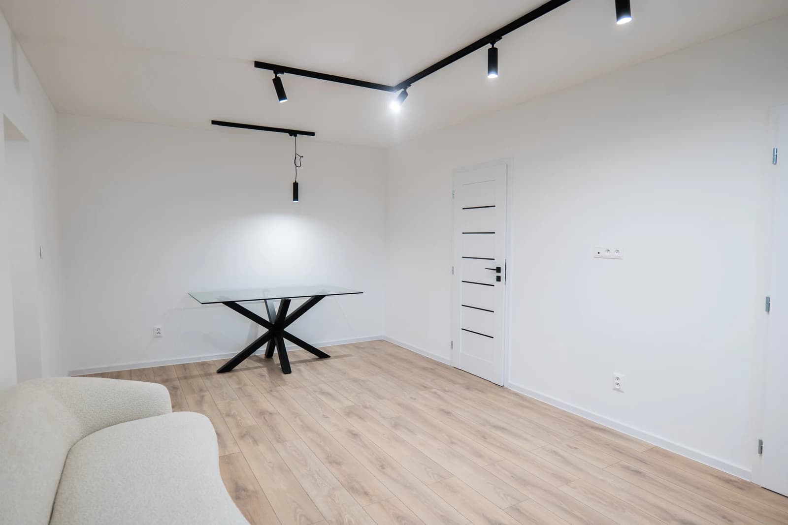 Štýlová tmavá kuchyňa s moderným osvetlením, zlatými akcentmi a elegantným jedálenským stolom.