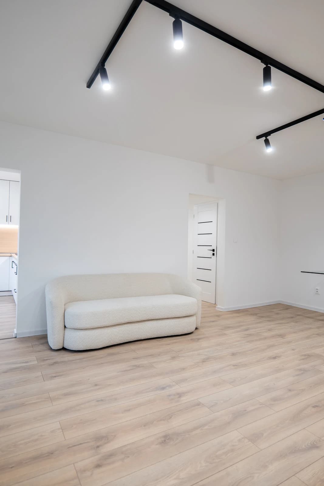 Štýlová tmavá kuchyňa s moderným osvetlením, zlatými akcentmi a elegantným jedálenským stolom.