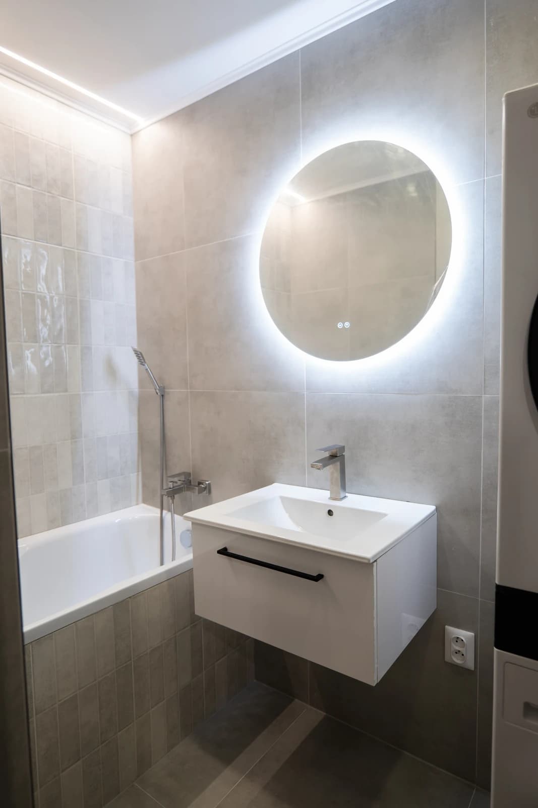 Štýlová tmavá kuchyňa s moderným osvetlením, zlatými akcentmi a elegantným jedálenským stolom.