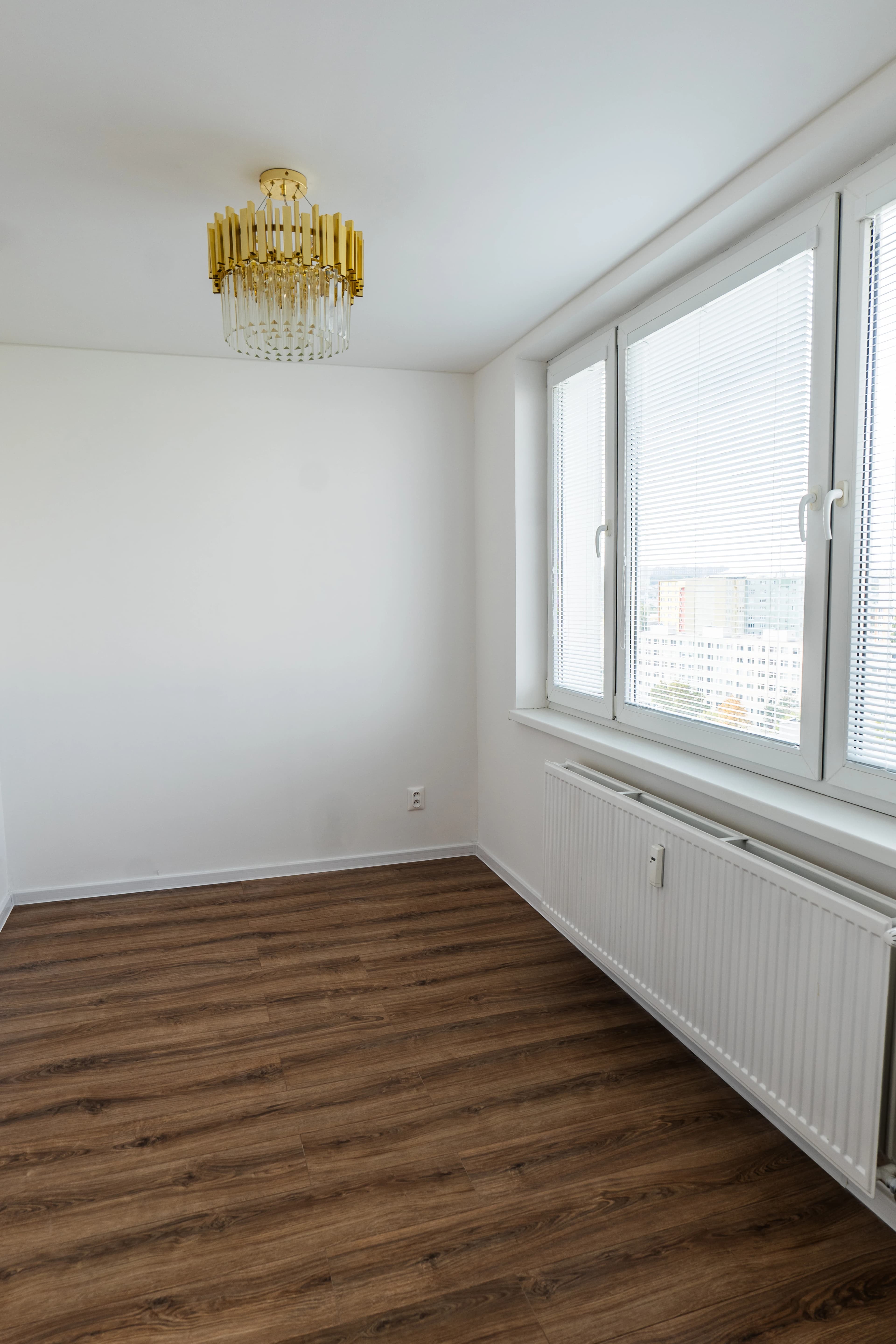 Štýlová tmavá kuchyňa s moderným osvetlením, zlatými akcentmi a elegantným jedálenským stolom.