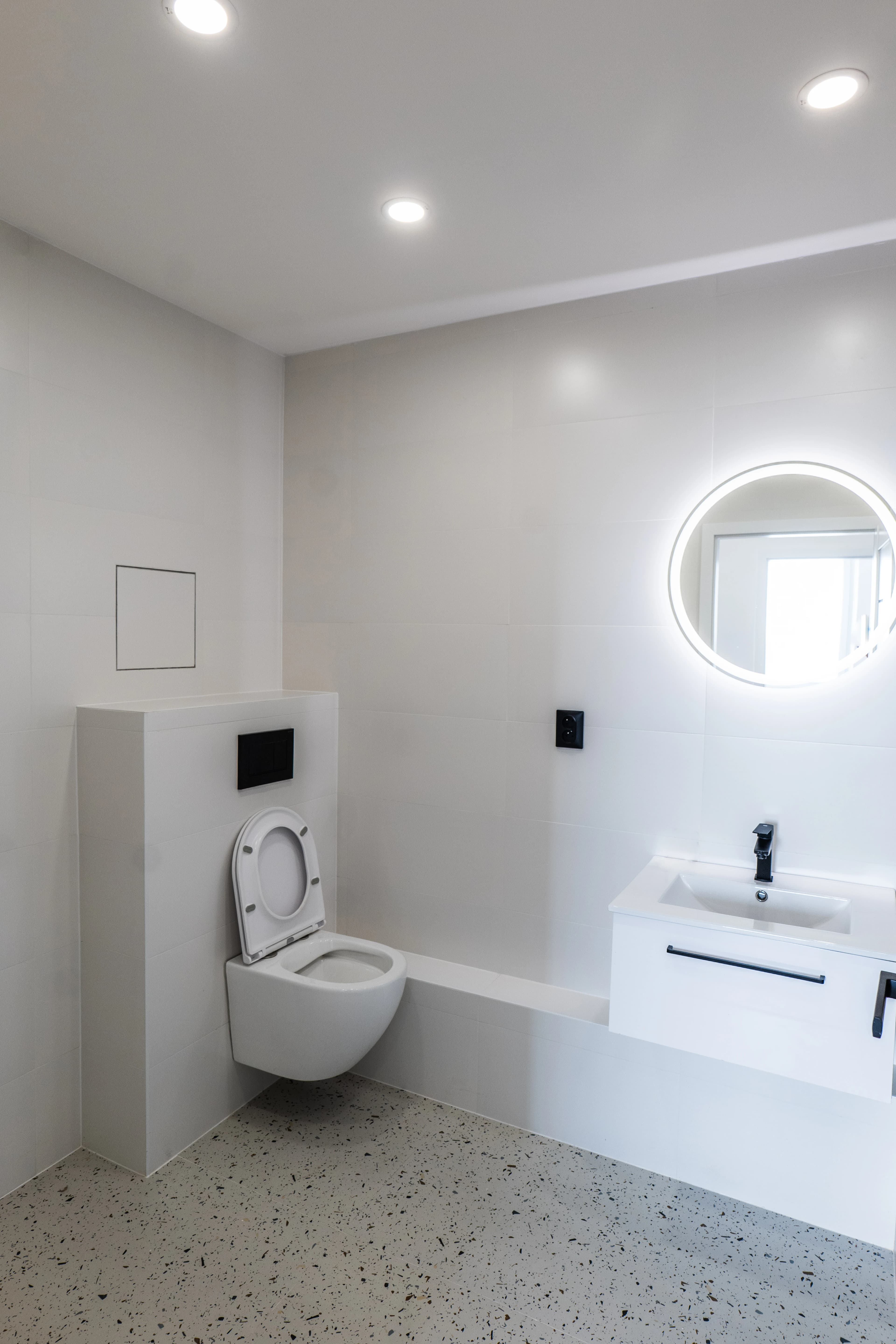 Štýlová tmavá kuchyňa s moderným osvetlením, zlatými akcentmi a elegantným jedálenským stolom.