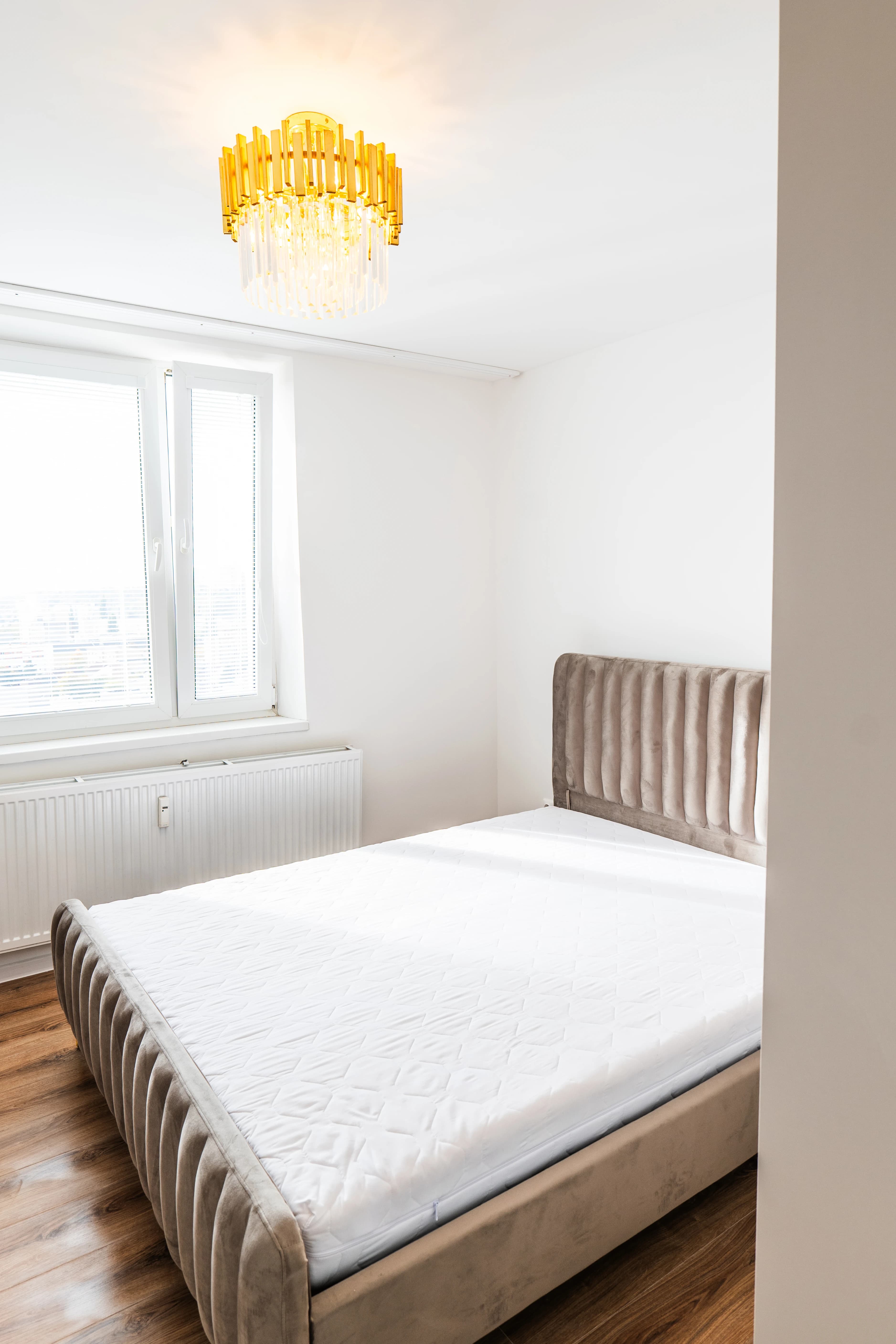 Štýlová tmavá kuchyňa s moderným osvetlením, zlatými akcentmi a elegantným jedálenským stolom.