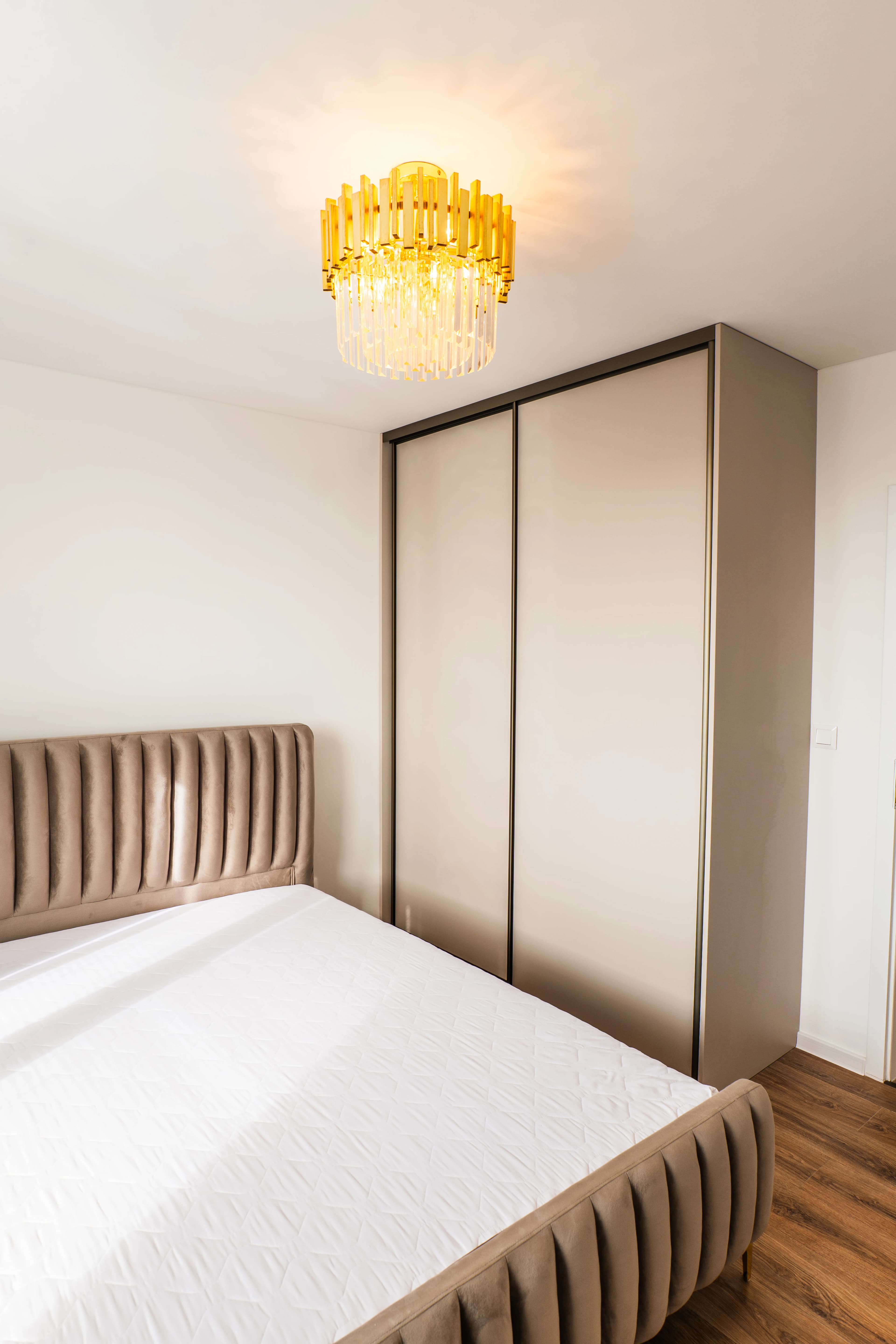 Štýlová tmavá kuchyňa s moderným osvetlením, zlatými akcentmi a elegantným jedálenským stolom.