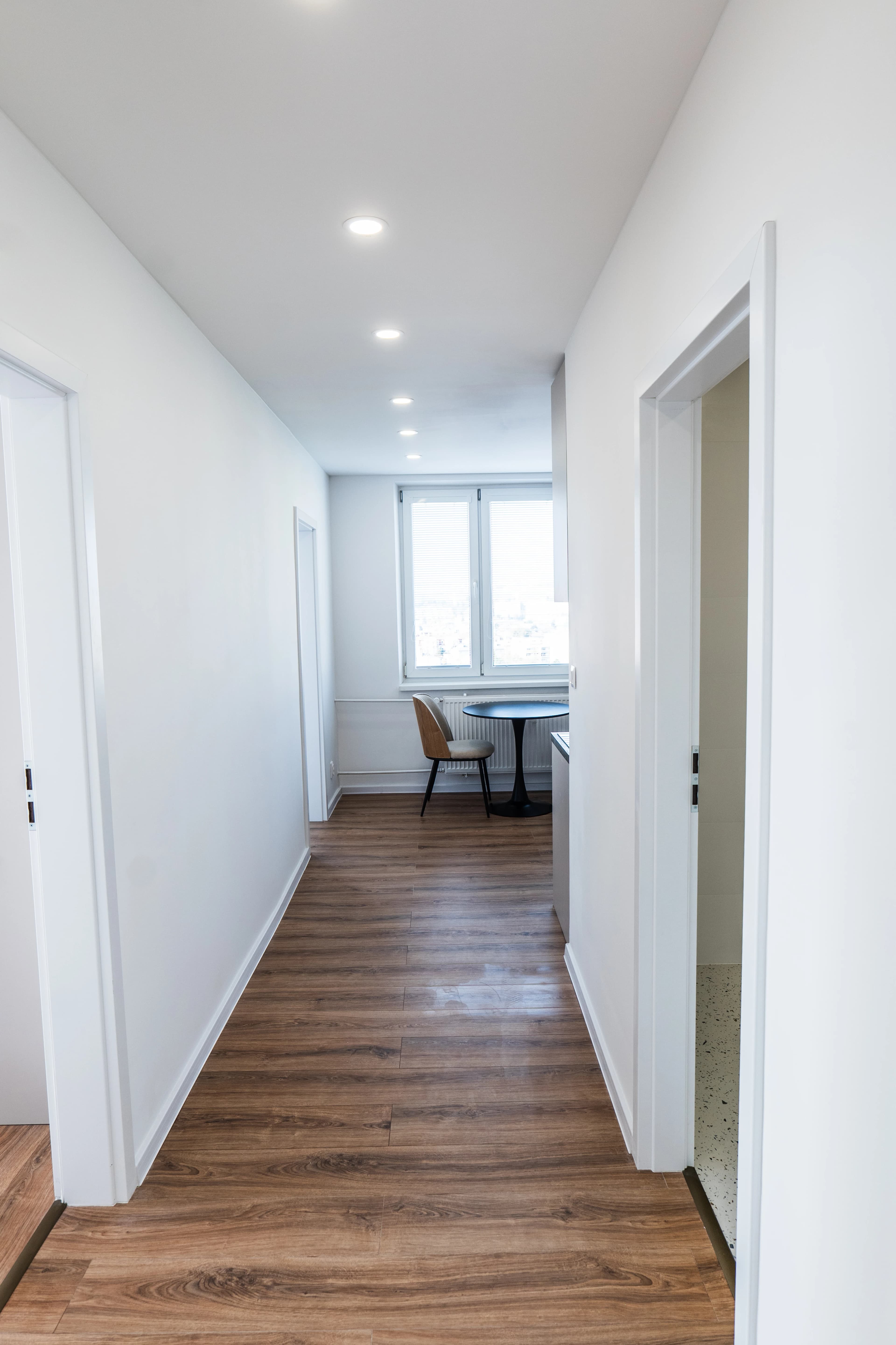 Štýlová tmavá kuchyňa s moderným osvetlením, zlatými akcentmi a elegantným jedálenským stolom.