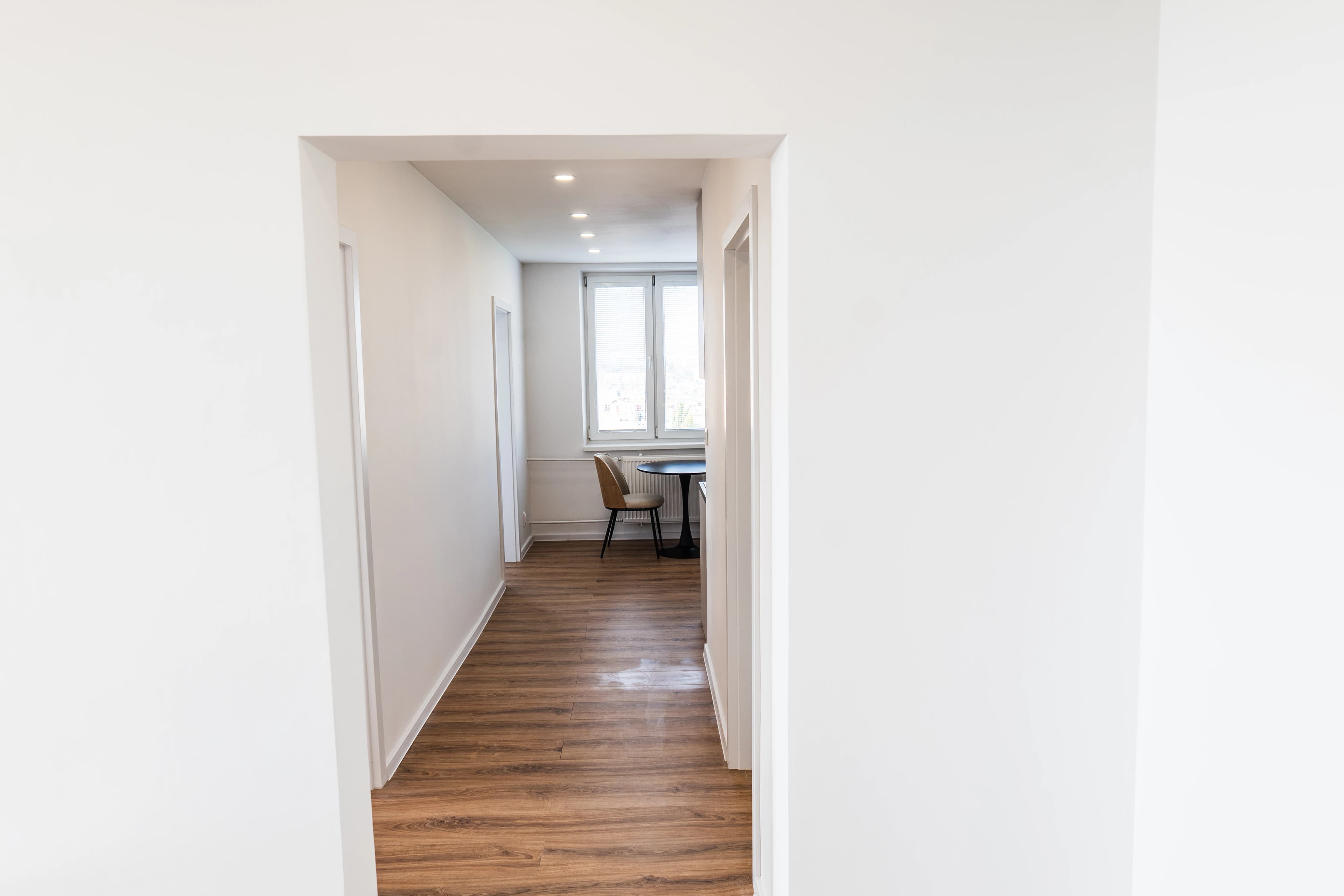 Štýlová tmavá kuchyňa s moderným osvetlením, zlatými akcentmi a elegantným jedálenským stolom.