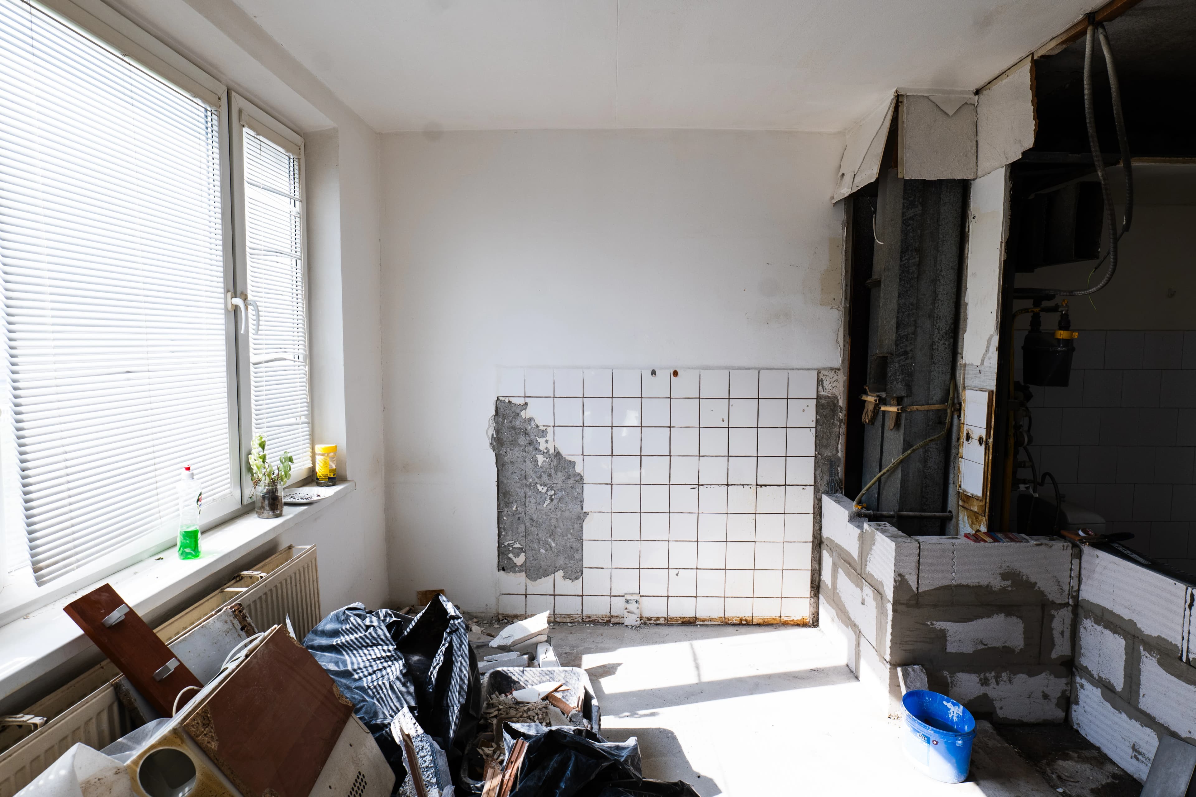 Štýlová tmavá kuchyňa s moderným osvetlením, zlatými akcentmi a elegantným jedálenským stolom.