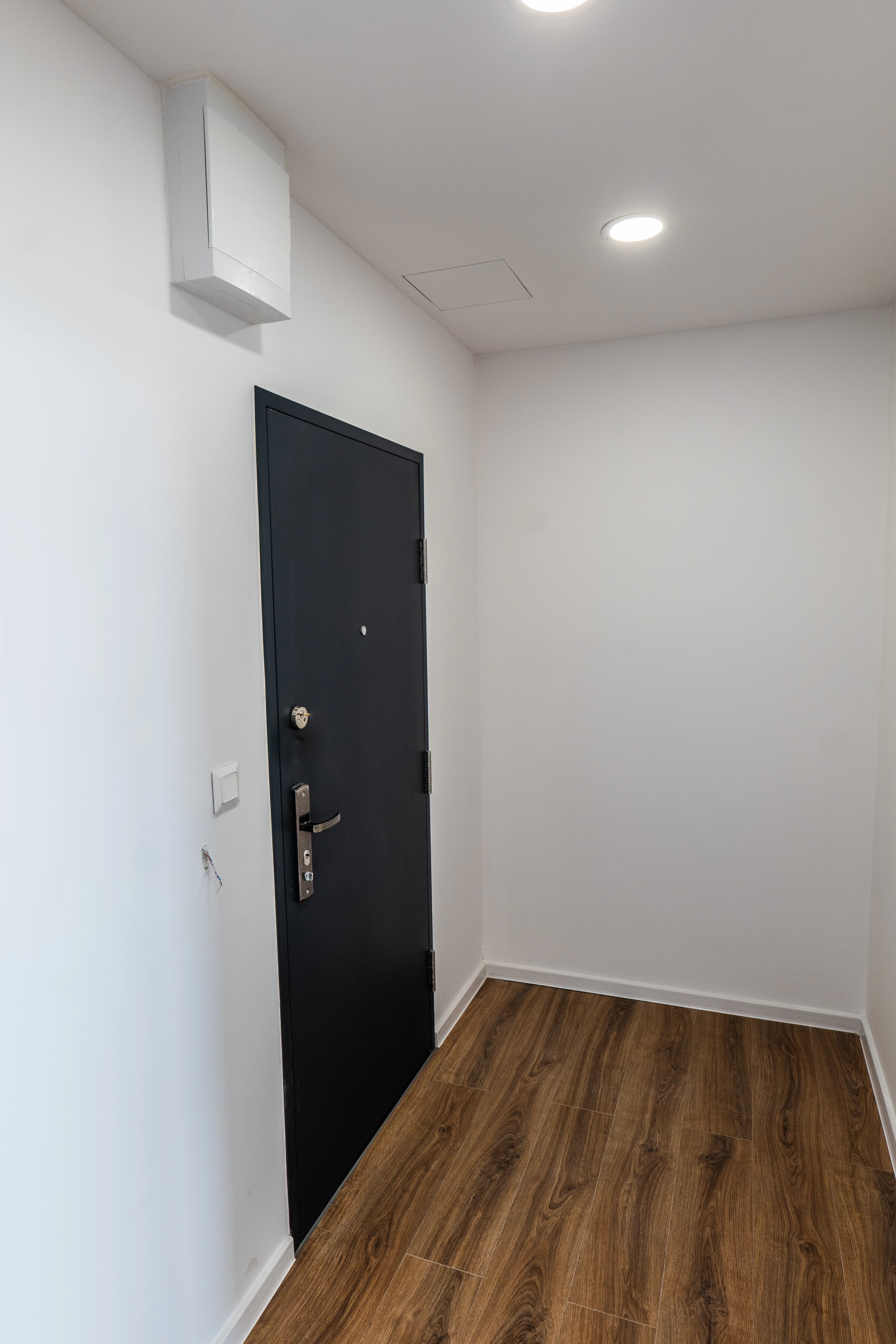 Štýlová tmavá kuchyňa s moderným osvetlením, zlatými akcentmi a elegantným jedálenským stolom.