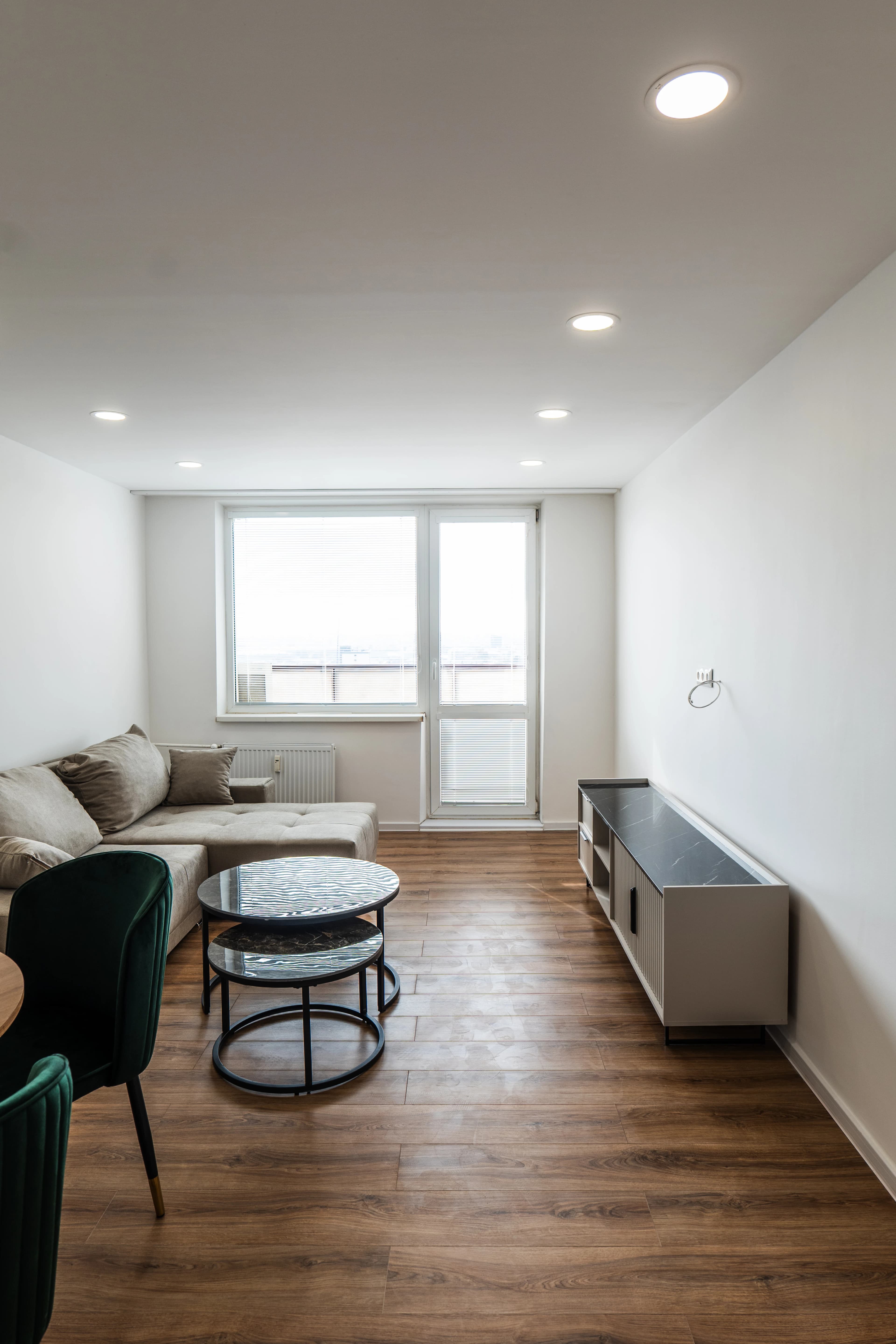 Štýlová tmavá kuchyňa s moderným osvetlením, zlatými akcentmi a elegantným jedálenským stolom.