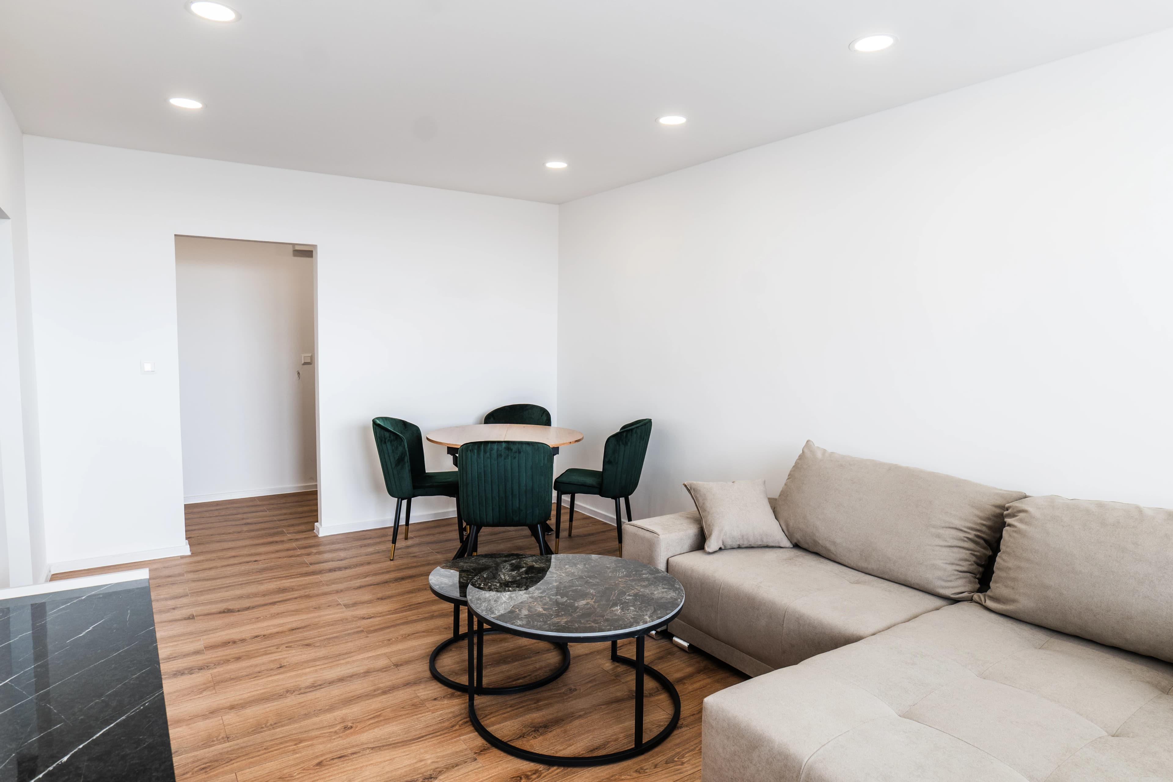 Štýlová tmavá kuchyňa s moderným osvetlením, zlatými akcentmi a elegantným jedálenským stolom.