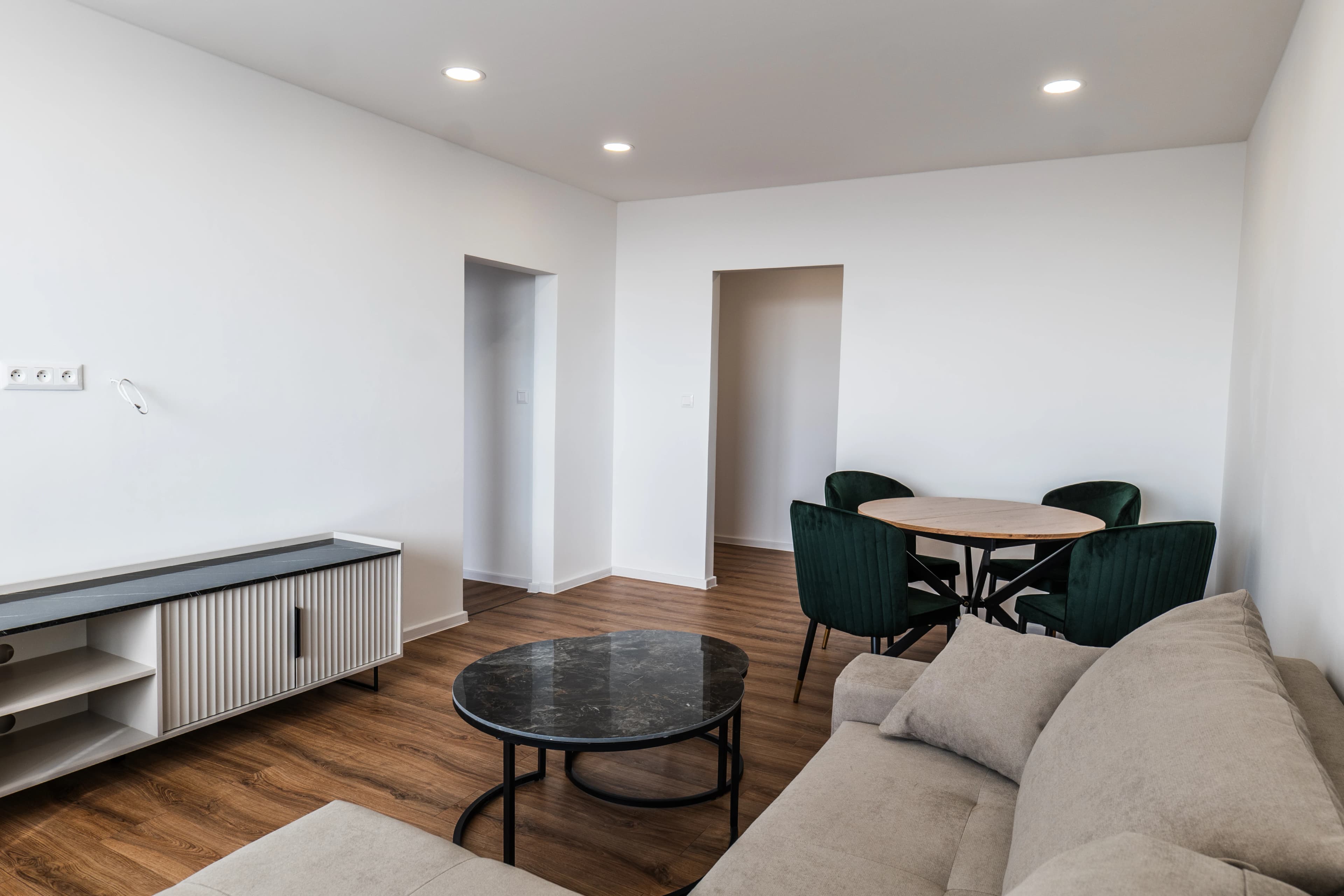 Štýlová tmavá kuchyňa s moderným osvetlením, zlatými akcentmi a elegantným jedálenským stolom.