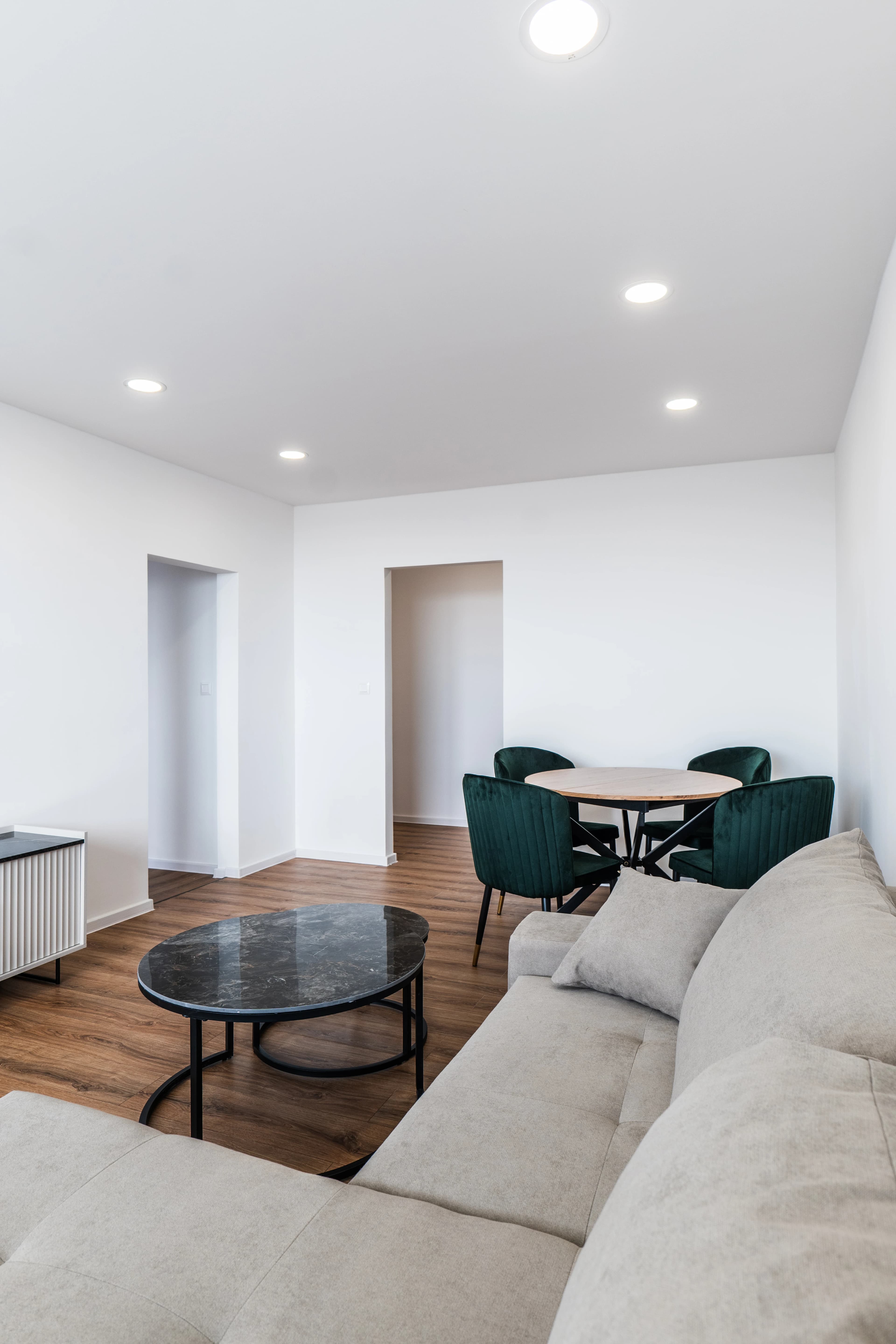 Štýlová tmavá kuchyňa s moderným osvetlením, zlatými akcentmi a elegantným jedálenským stolom.