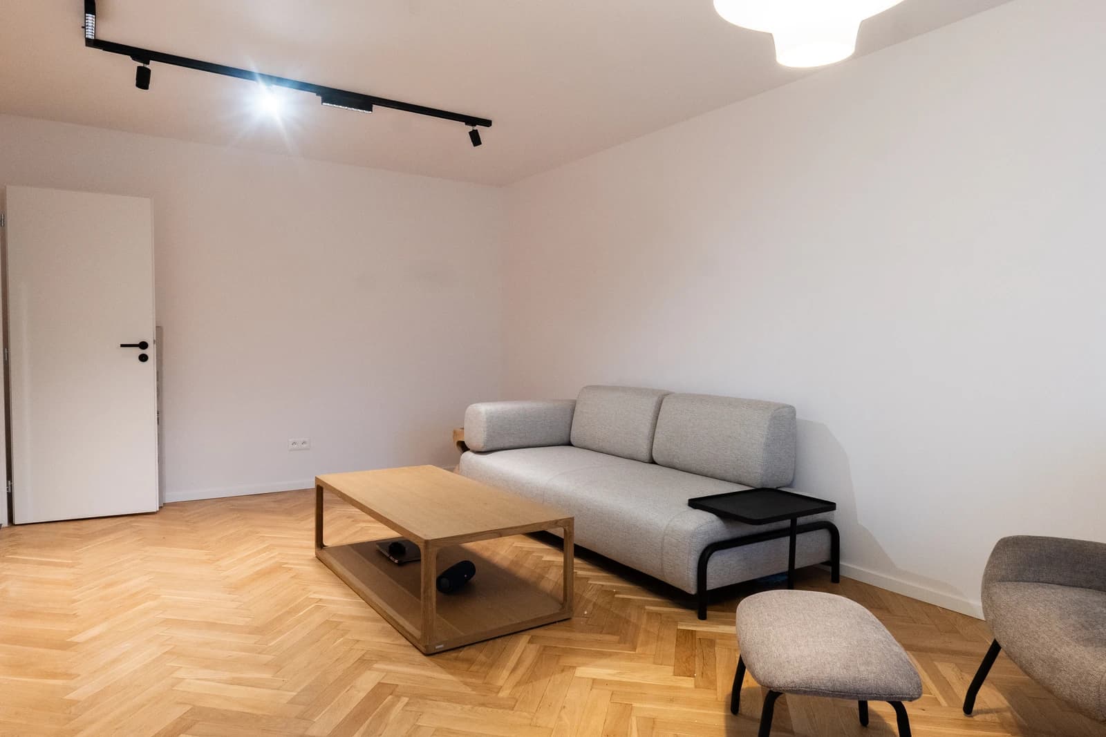 Štýlová tmavá kuchyňa s moderným osvetlením, zlatými akcentmi a elegantným jedálenským stolom.