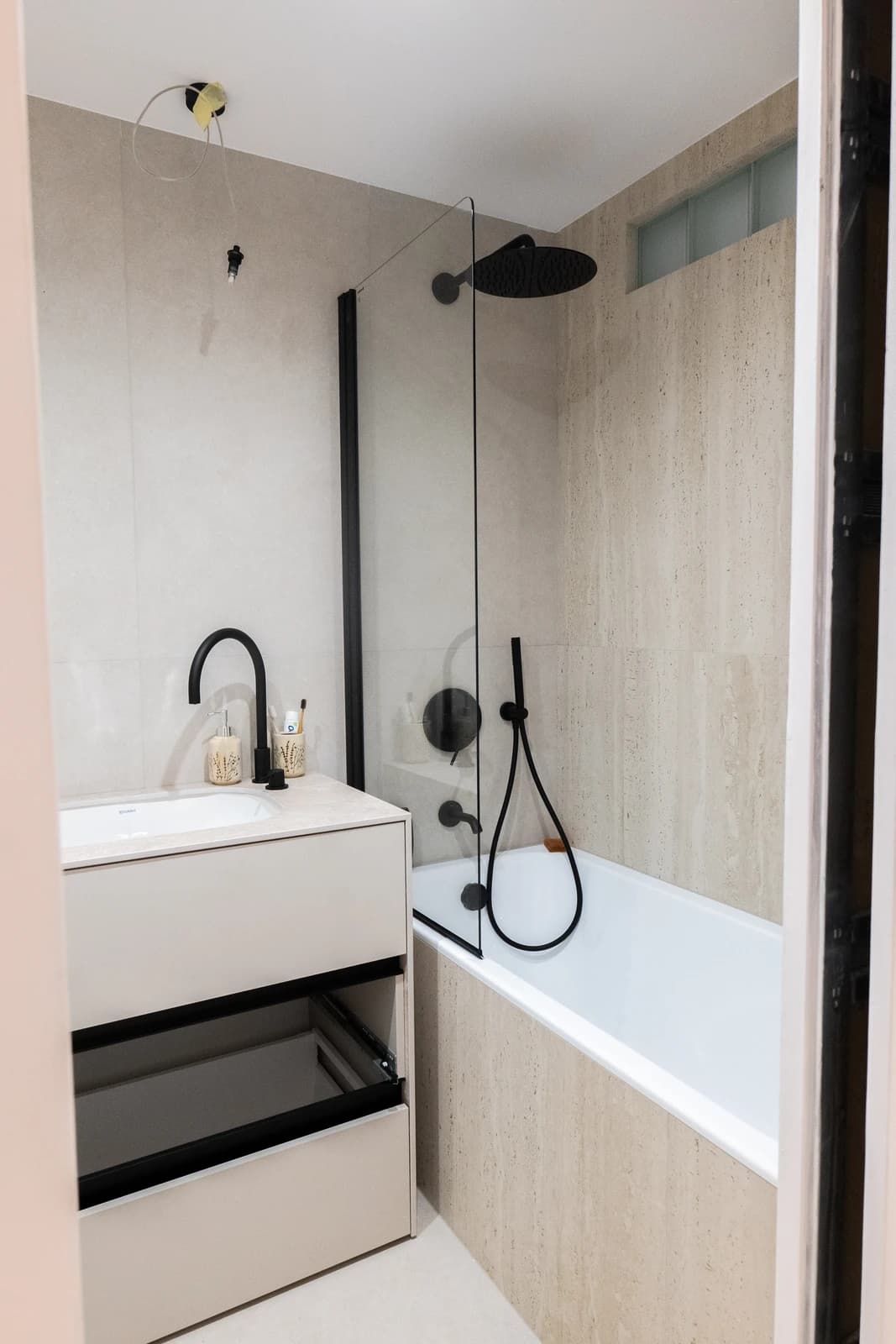 Štýlová tmavá kuchyňa s moderným osvetlením, zlatými akcentmi a elegantným jedálenským stolom.