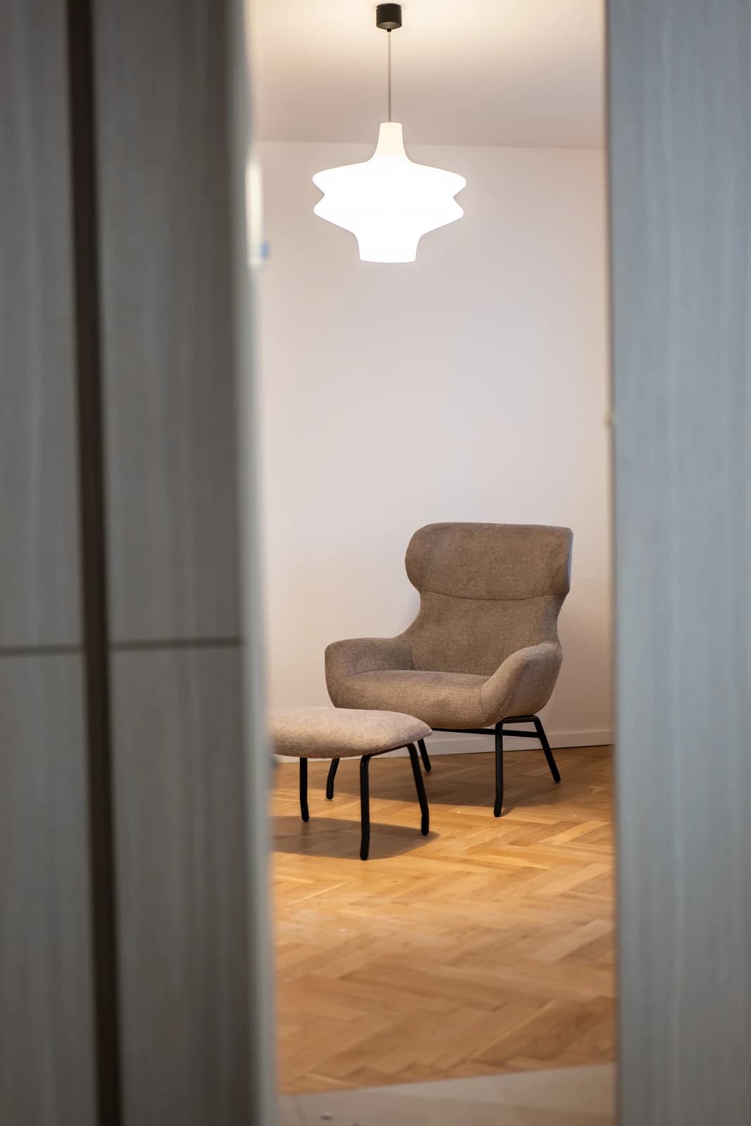 Štýlová tmavá kuchyňa s moderným osvetlením, zlatými akcentmi a elegantným jedálenským stolom.