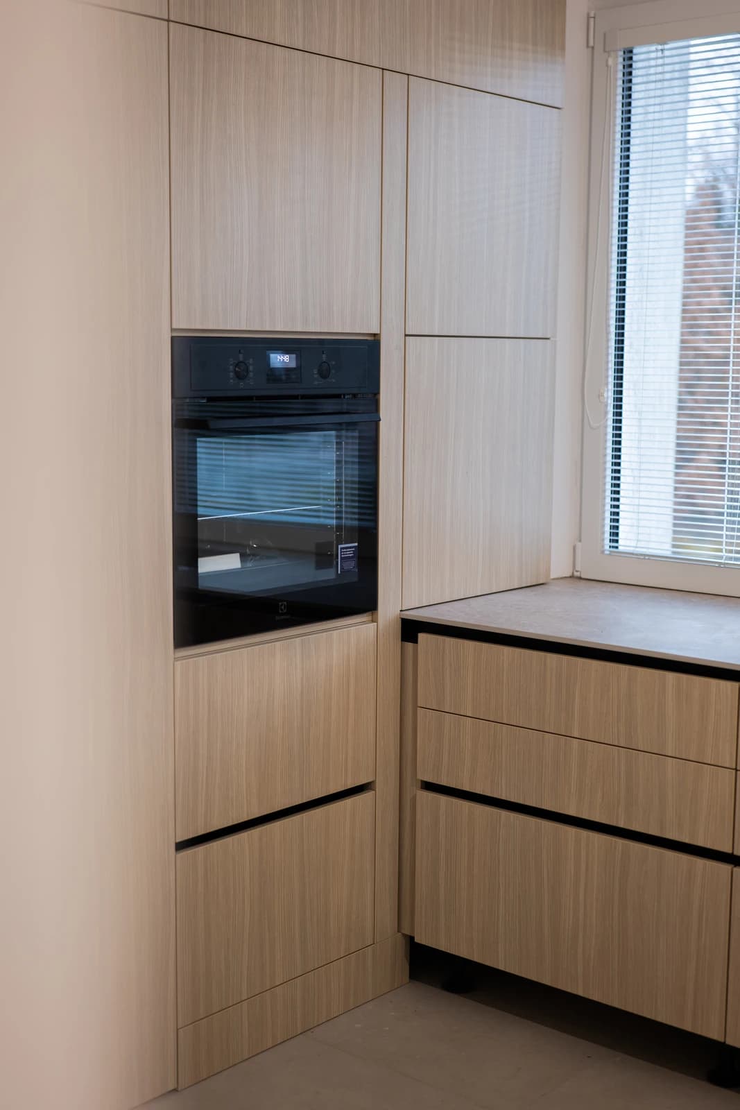 Štýlová tmavá kuchyňa s moderným osvetlením, zlatými akcentmi a elegantným jedálenským stolom.