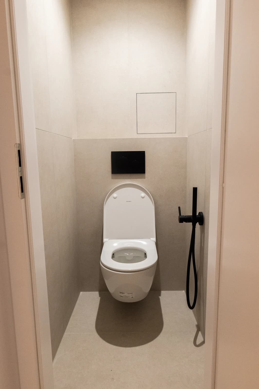 Štýlová tmavá kuchyňa s moderným osvetlením, zlatými akcentmi a elegantným jedálenským stolom.