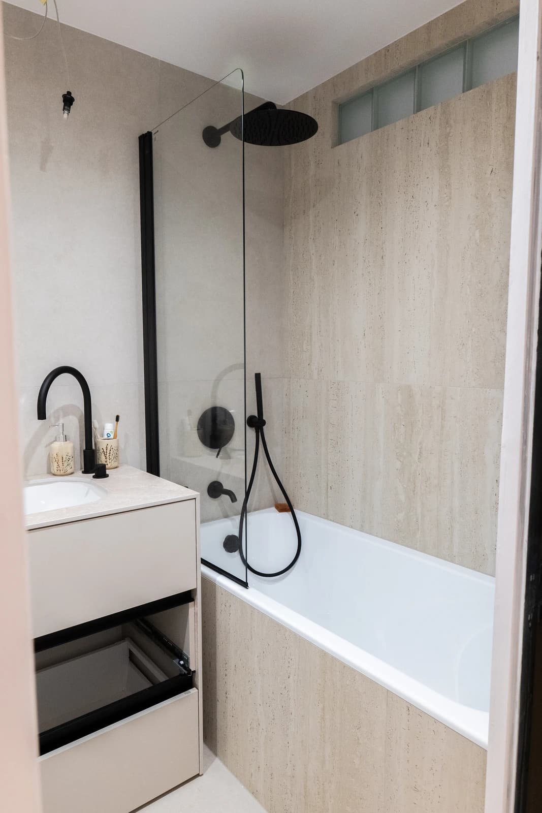 Štýlová tmavá kuchyňa s moderným osvetlením, zlatými akcentmi a elegantným jedálenským stolom.